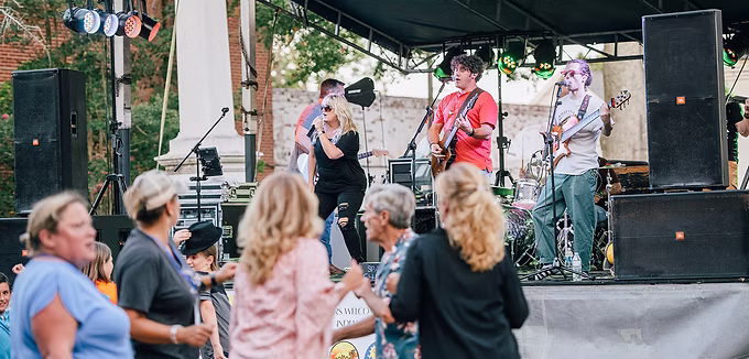 Performers on a stage with people dancing outside