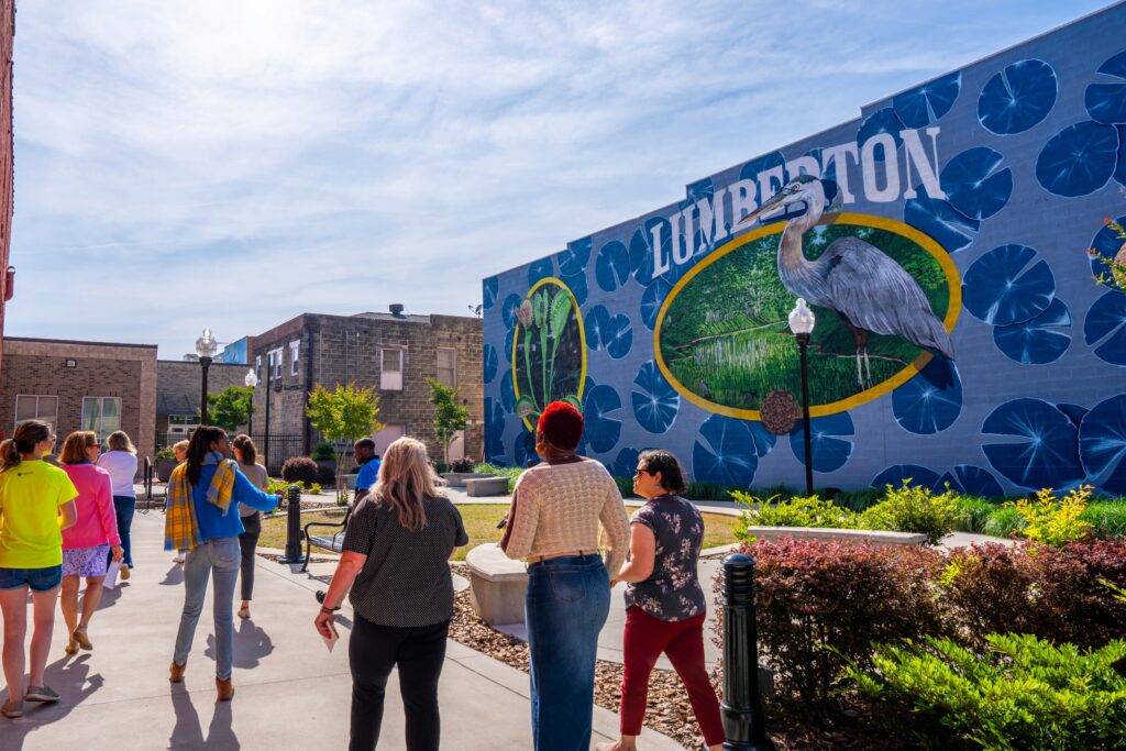 People walking by Lumberton Art Mural